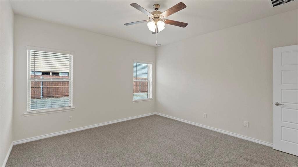 750 Hart Leaf Lane, Lavon, TX 75166 Carpeted interior room with white walls, two windows featuring horizontal blinds, and a ceiling fan with integrated lighting