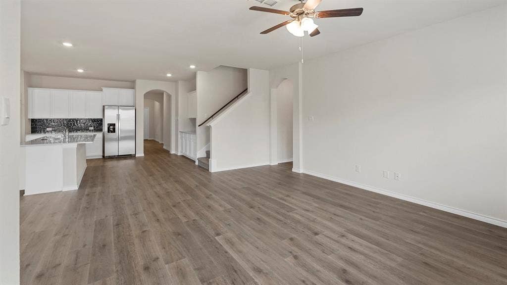 750 Hart Leaf Lane, Lavon, TX 75166 Open-concept living space featuring wood-finish flooring, a contemporary kitchen with white cabinetry, a mosaic tile backsplash, stainless steel appliances, and a central island with a sink