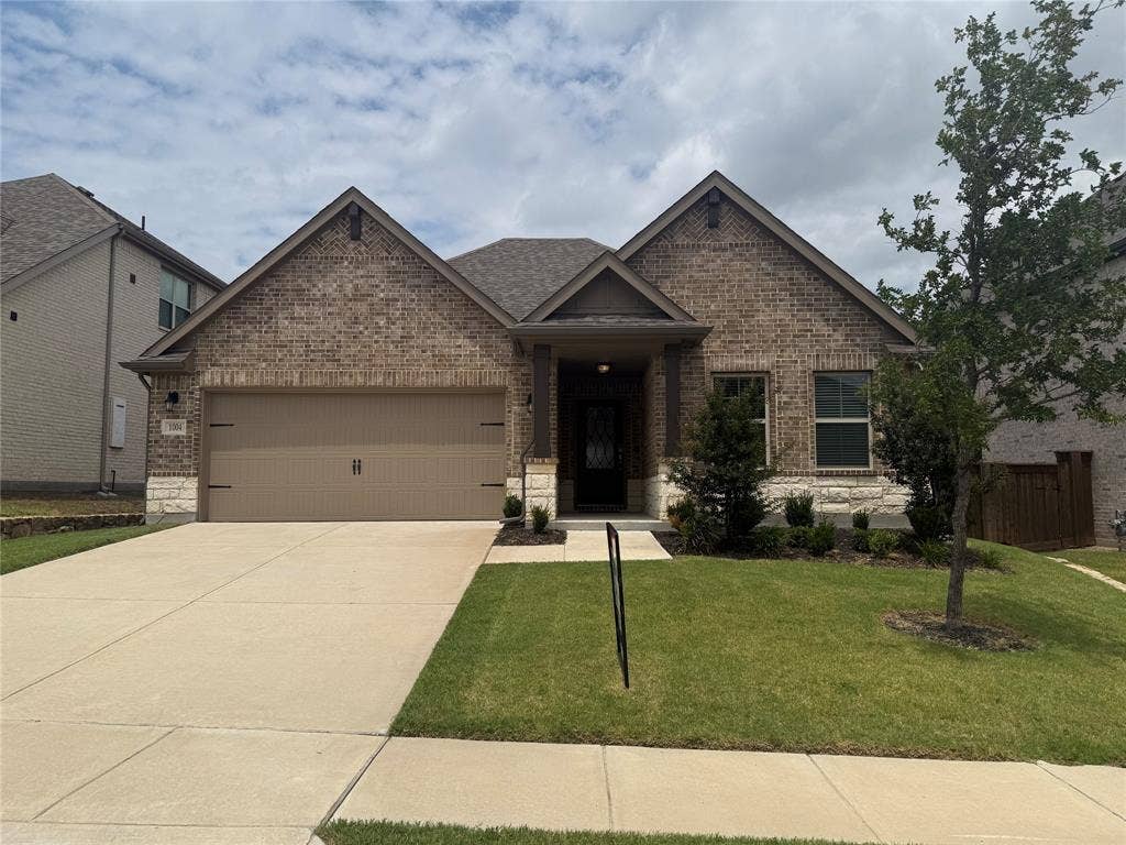 1004 Copper Smith Way, Forney, TX 75126 Brick and stone facade with a covered entry, attached two-car garage, and concrete driveway