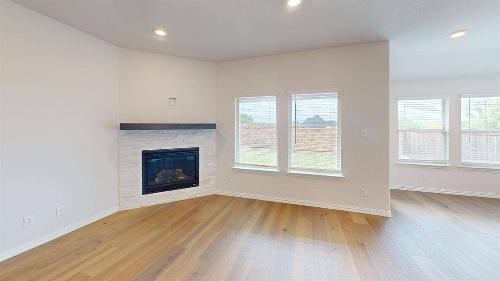1004 Copper Smith Way, Forney, TX 75126 Corner fireplace with a stone surround and wood mantel