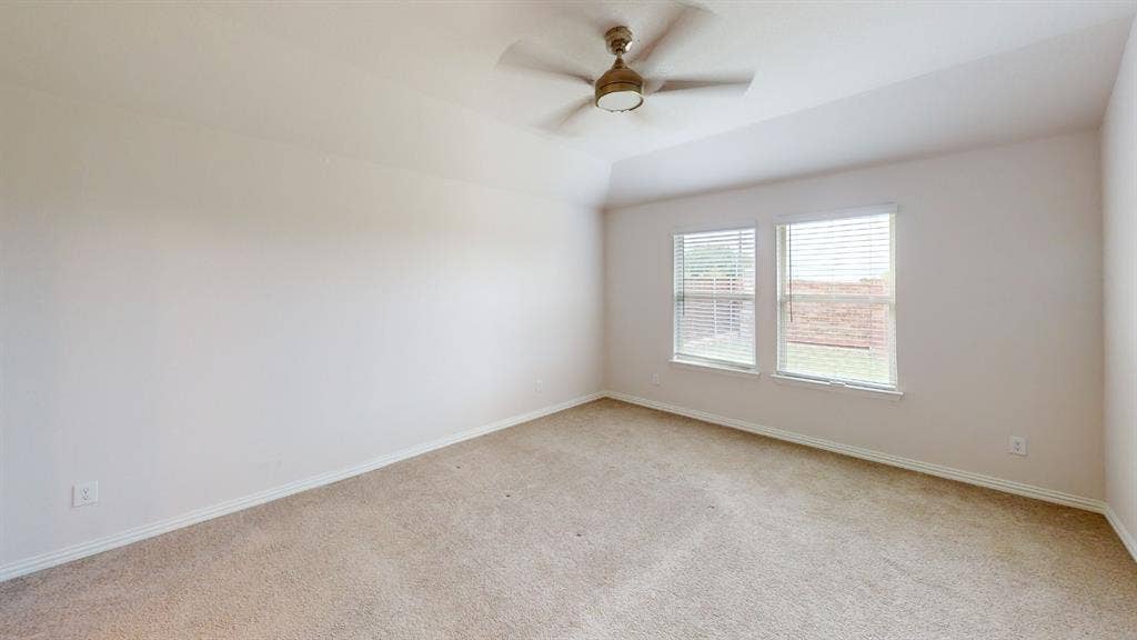 1004 Copper Smith Way, Forney, TX 75126 Carpeted room with a vaulted ceiling, two windows featuring blinds, and a ceiling fan