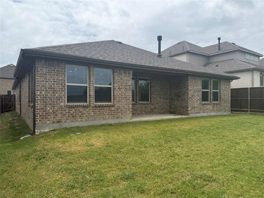 1004 Copper Smith Way, Forney, TX 75126 Brick exterior with shingle roofing, featuring a covered concrete patio and a lush lawn