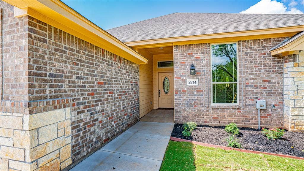 2714 Austin Drive, Granbury, TX 76048 Front entrance of home with landscaped flowerbeds