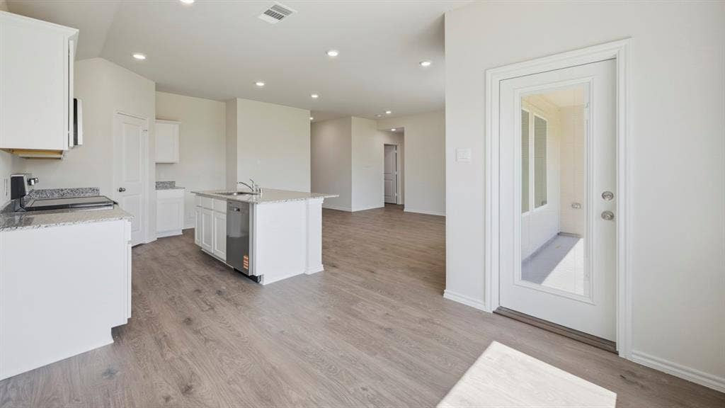 443 Epiphany Lane, Lavon, TX 75166 Open-concept kitchen featuring white cabinetry, granite countertops, a central island with a sink, stainless steel dishwasher, and recessed lighting