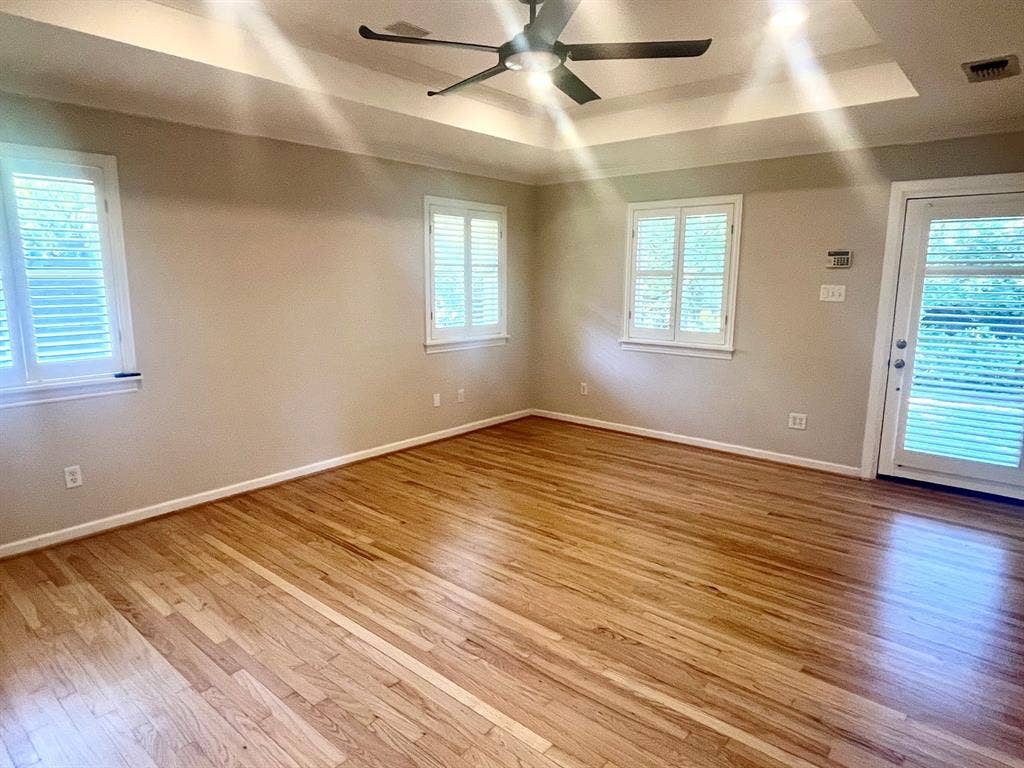 10409 Remington Lane, Dallas, TX 75229 Hardwood flooring throughout, tray ceiling, ceiling fan, white window shutters, and a glass-paneled door