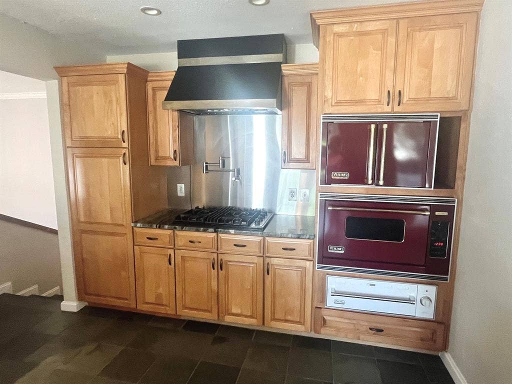 10409 Remington Lane, Dallas, TX 75229 Built-in gas cooktop with a stainless steel backsplash, integrated range hood, wood-finish cabinetry, and dark tiled flooring