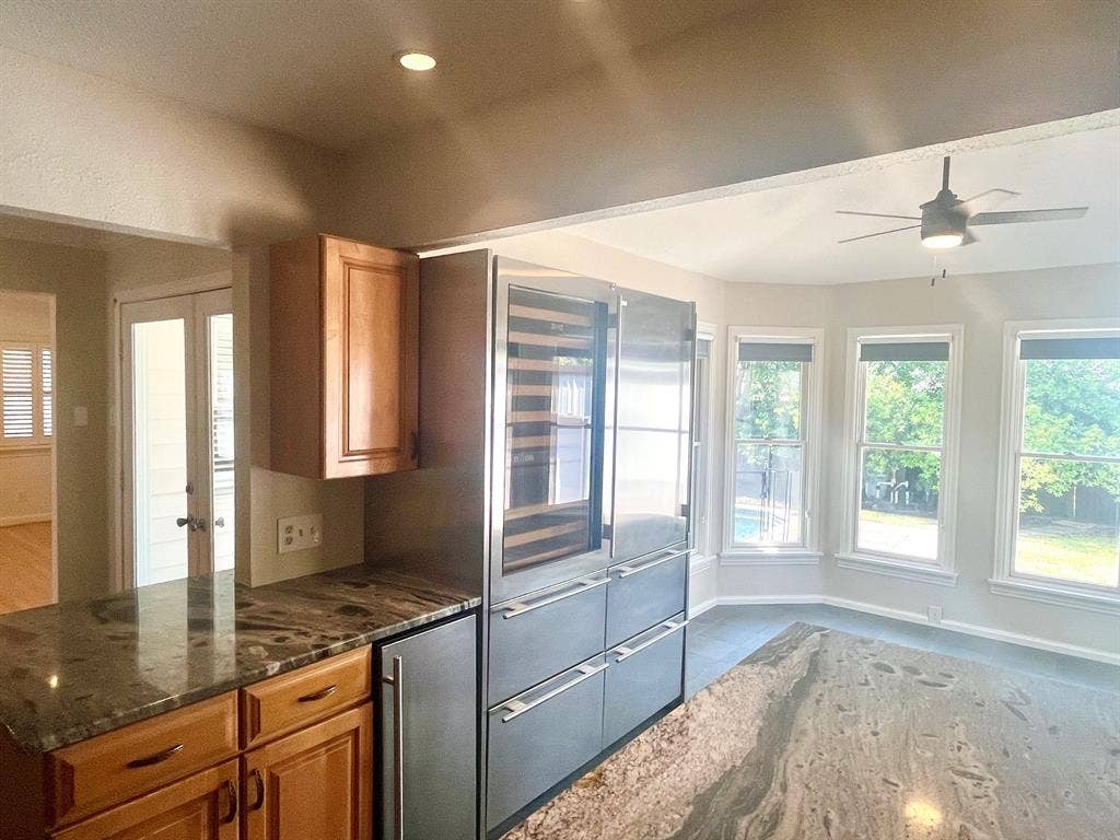 10409 Remington Lane, Dallas, TX 75229 Stainless steel appliances, built-in wine refrigeration, wood cabinetry, stone countertops, and a ceiling fan