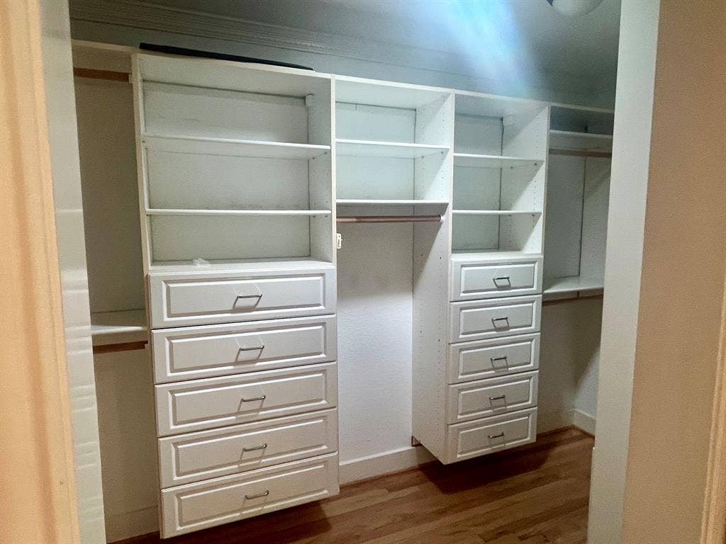 10409 Remington Lane, Dallas, TX 75229 Custom walk-in closet featuring built-in white cabinetry with multiple shelving units, five spacious drawers with metal hardware, and a central hanging rod for optimal storage and organization