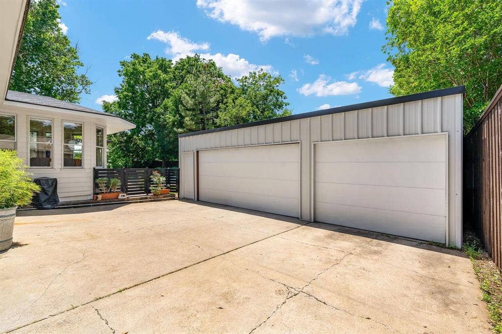 10409 Remington Lane, Dallas, TX 75229 Six-car garage with white paneled doors, concrete driveway, and a privacy fence