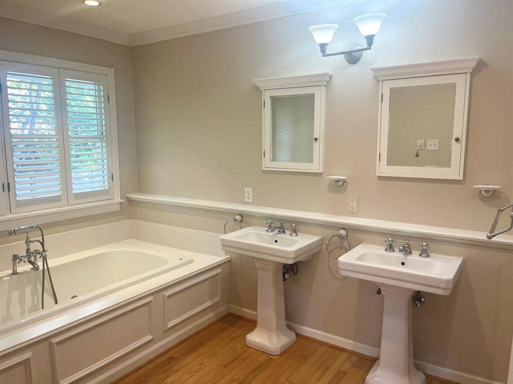 10409 Remington Lane, Dallas, TX 75229 Built-in soaking tub with panel detailing, dual pedestal sinks, and two recessed medicine cabinets