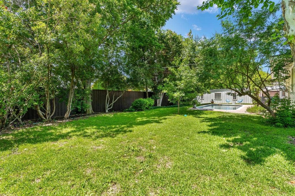 10409 Remington Lane, Dallas, TX 75229 Expansive green lawn, mature trees, privacy fencing, and a built-in swimming pool with surrounding hardscaping