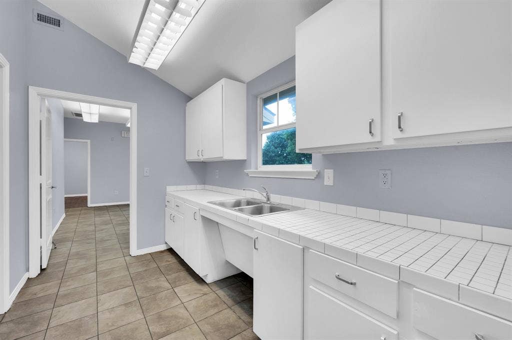 214 W Belt Line Road, #B, Cedar Hill, TX 75104 Tile flooring, vaulted ceiling, white cabinetry, double basin sink, and tile countertops