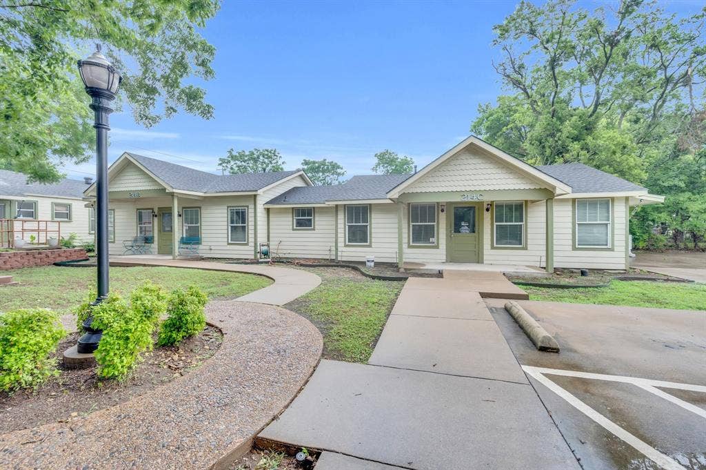 214 W Belt Line Road, #B, Cedar Hill, TX 75104 Exterior featuring light-colored siding with green trim, gabled rooflines, multiple windows, and a concrete pathway