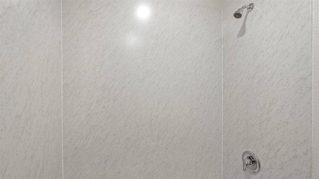 809 Brook Lane, Josephine, TX 75135 Shower enclosure with light-toned wall panels, chrome shower head, and chrome single-handle control
