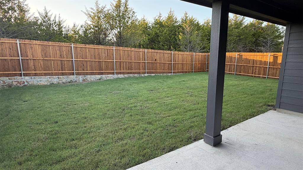 809 Brook Lane, Josephine, TX 75135 Expansive grassy yard with a wood fence featuring a stone base