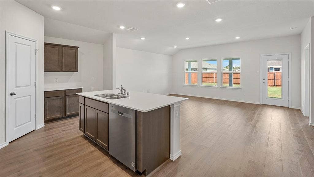 809 Brook Lane, Josephine, TX 75135 Open-concept living area with wood-finish flooring, recessed lighting, and a kitchen island featuring a stainless steel dishwasher