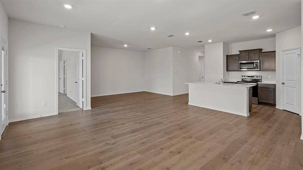 809 Brook Lane, Josephine, TX 75135 Expansive room featuring wood-finish flooring, recessed lighting, and a kitchen island with integrated sink