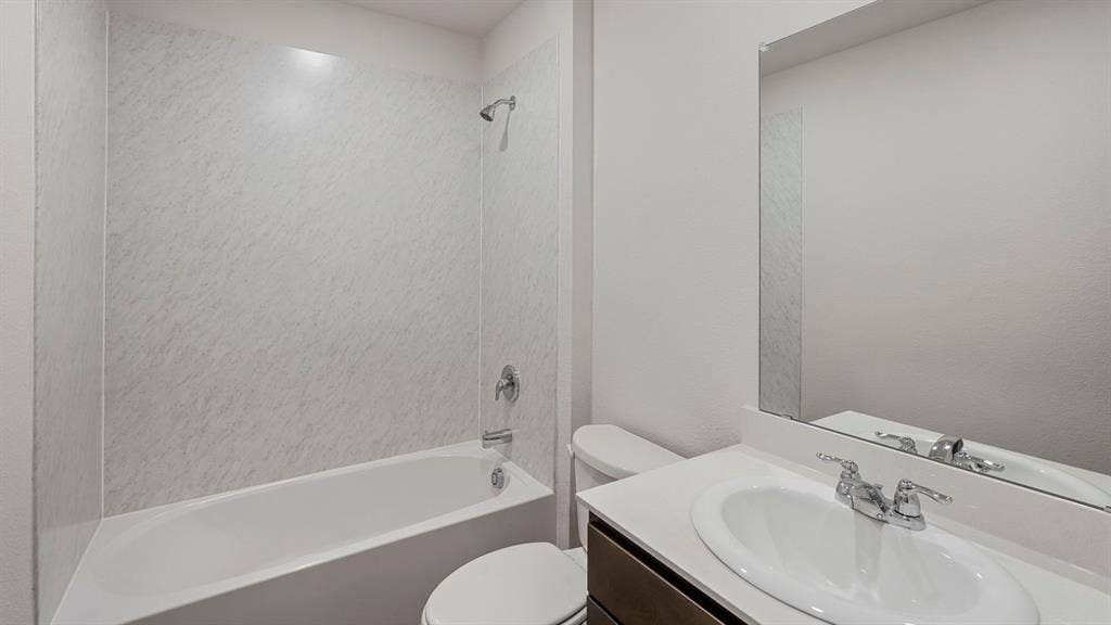 809 Brook Lane, Josephine, TX 75135 White bathtub with integrated shower, chrome fixtures, a modern vanity with an integrated sink, and a large wall-mounted mirror