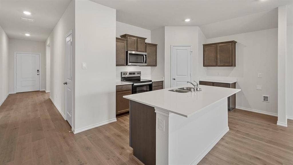 809 Brook Lane, Josephine, TX 75135 Kitchen featuring wood-finish flooring, recessed lighting, a kitchen island with an undermount sink, and stainless steel appliances