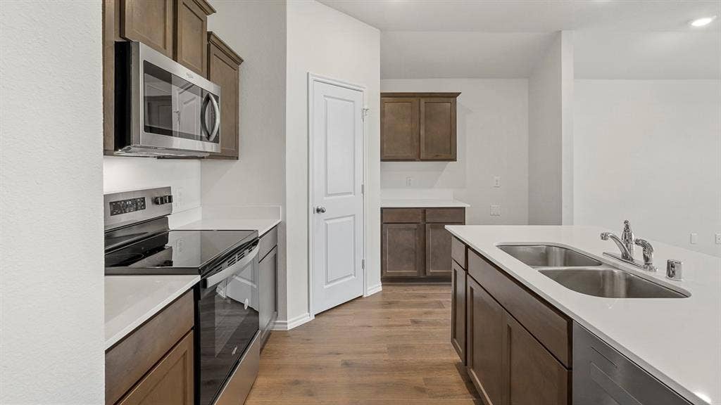 809 Brook Lane, Josephine, TX 75135 Stainless steel appliances, wood-finish flooring, white countertops, dark wood cabinetry, and a double basin sink