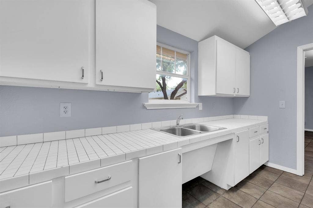 214 W Belt Line Road, #C, Cedar Hill, TX 75104 White cabinetry, tile countertops, stainless steel double-basin sink, and a window with exterior visibility