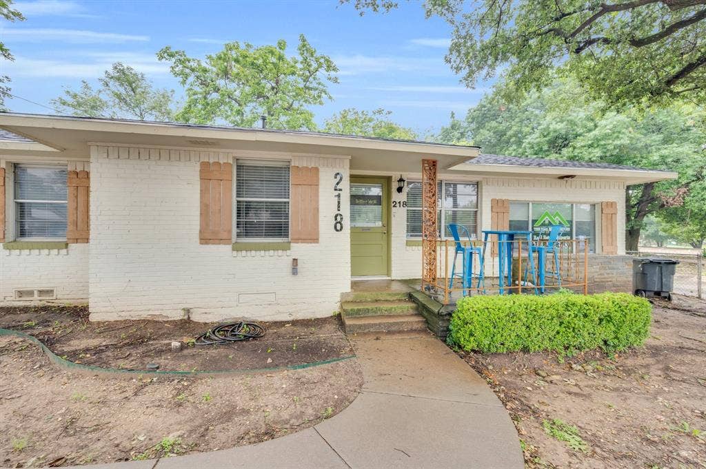 214 W Belt Line Road, #C, Cedar Hill, TX 75104 White brick exterior with wood-tone shutters, a sage green door, and a concrete pathway leading to the entrance