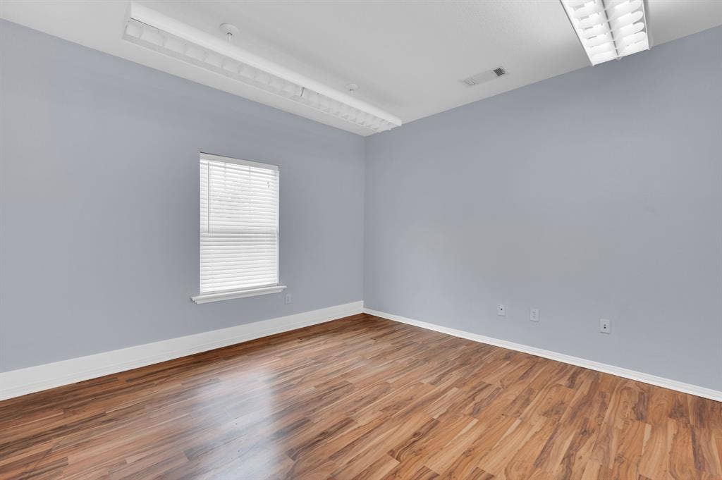 214 W Belt Line Road, #C, Cedar Hill, TX 75104 Wood-finish flooring, light blue wall paint, white trim, window with blinds, and ceiling-mounted fluorescent lighting