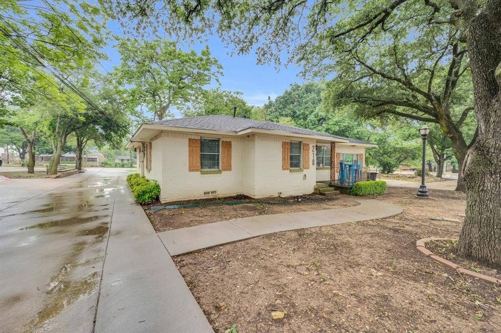 216 W Belt Line Road, Cedar Hill, TX 75104 Cream-colored brick exterior with wood shutters, concrete walkways, and mature trees