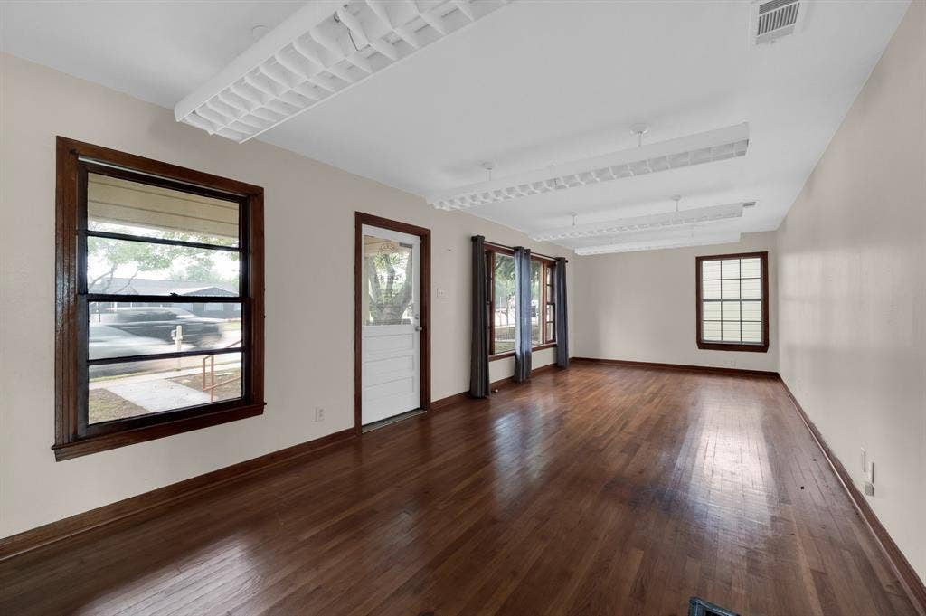 216 W Belt Line Road, Cedar Hill, TX 75104 Hardwood flooring, multiple windows with dark wood trim, white walls, white ceiling with integrated lighting, and a white paneled door