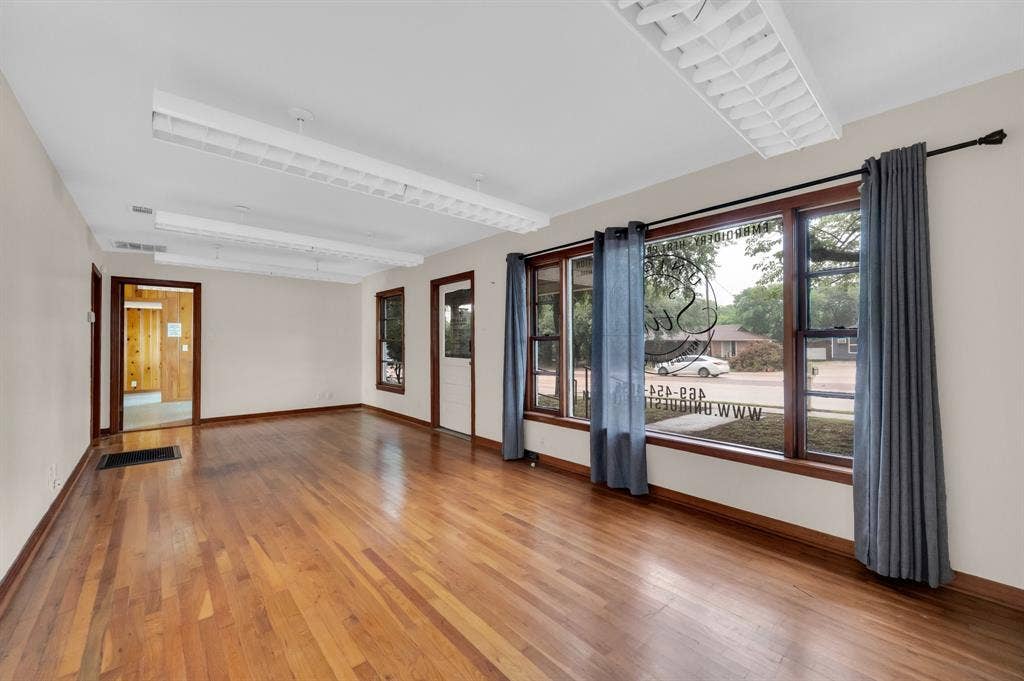 216 W Belt Line Road, Cedar Hill, TX 75104 Hardwood flooring with a gloss finish, multiple windows with wood trim, and overhead fluorescent lighting fixtures