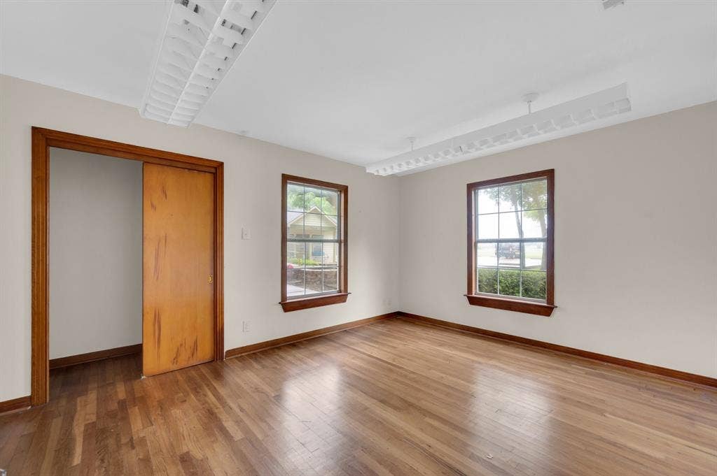 216 W Belt Line Road, Cedar Hill, TX 75104 Hardwood flooring throughout, two windows with wood trim, wood-paneled pocket door, and two ceiling-mounted light fixtures