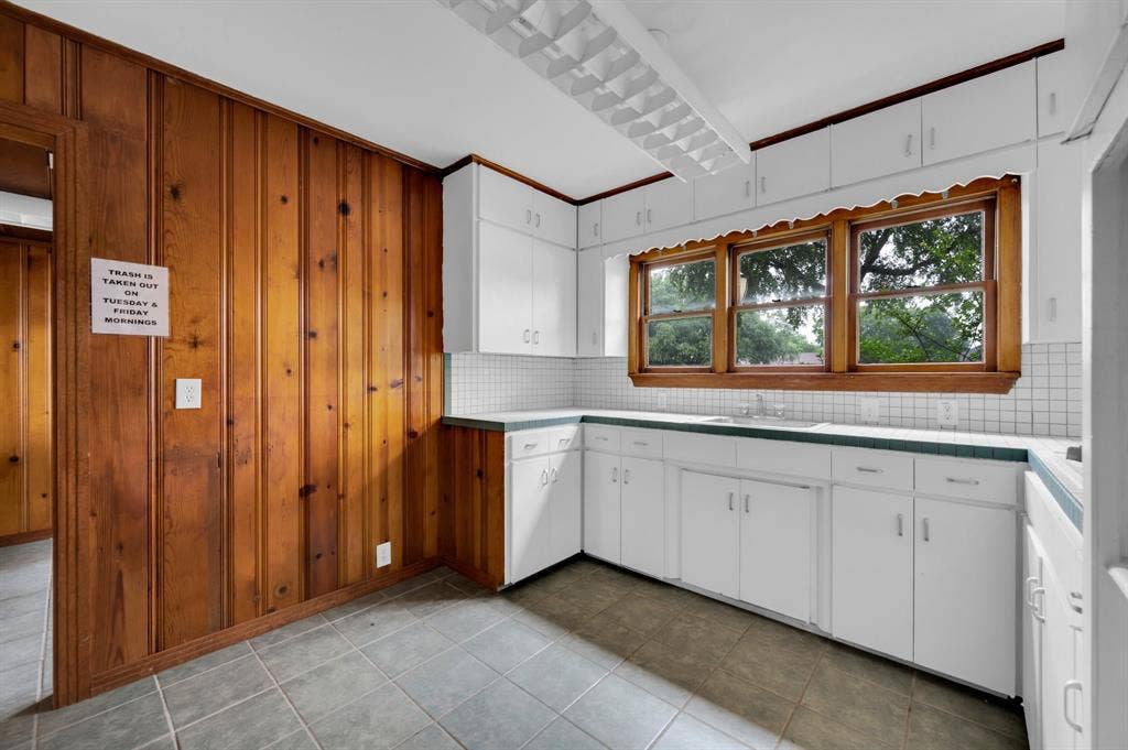216 W Belt Line Road, Cedar Hill, TX 75104 White cabinetry, wood paneling, tiled flooring, white subway tile backsplash, and a multi-pane window