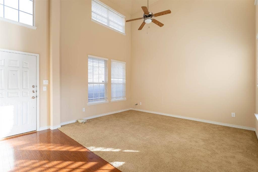 6509 Hickory Hill Drive, Plano, TX 75074 Two-story ceiling, multiple windows with blinds, ceiling fan, wood-finish flooring, and light-colored carpet