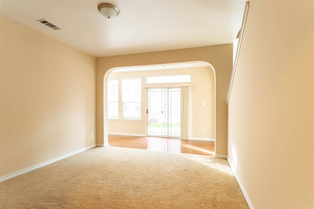 6509 Hickory Hill Drive, Plano, TX 75074 Archway entry to a room featuring wood-finish flooring, multiple windows, and a sliding glass door