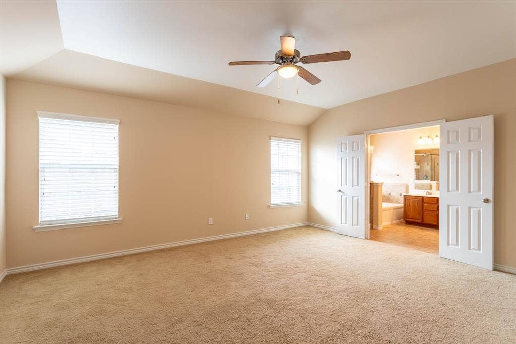 6509 Hickory Hill Drive, Plano, TX 75074 Vaulted ceiling featuring a ceiling fan, two windows with blinds, and carpeted flooring