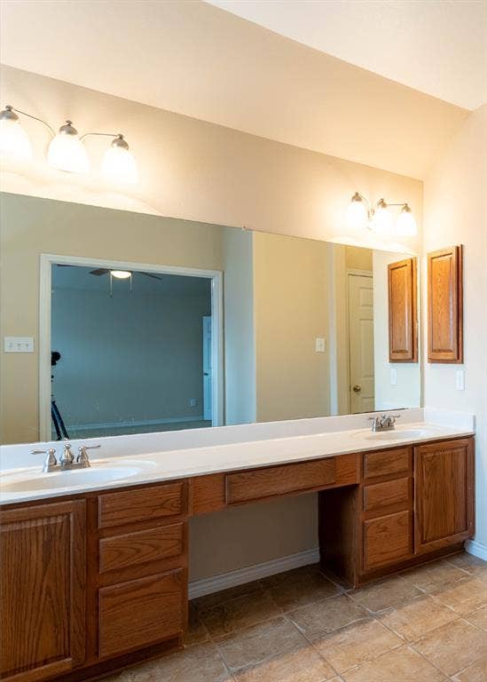 6509 Hickory Hill Drive, Plano, TX 75074 Dual vanity with undermount sinks and chrome fixtures, expansive wall-mounted mirror, wood-finish cabinetry, and tiled flooring