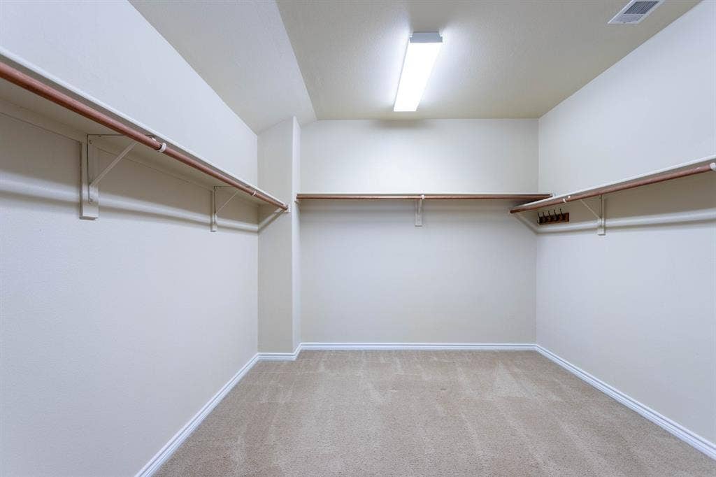 6509 Hickory Hill Drive, Plano, TX 75074 Spacious closet featuring multiple hanging rods, integrated shelving, and wall-to-wall carpeting