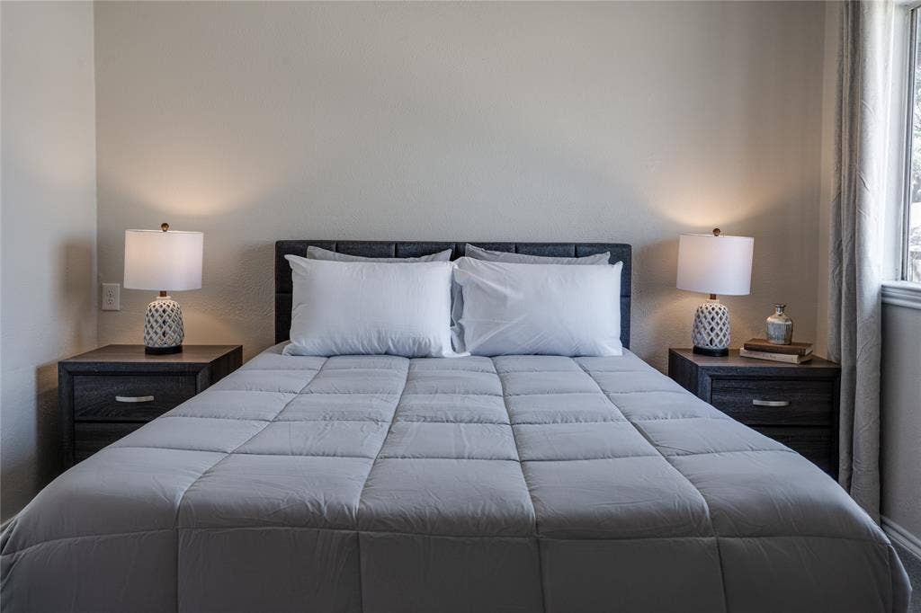 Textured headboard, window with drapes, and neutral wall tones