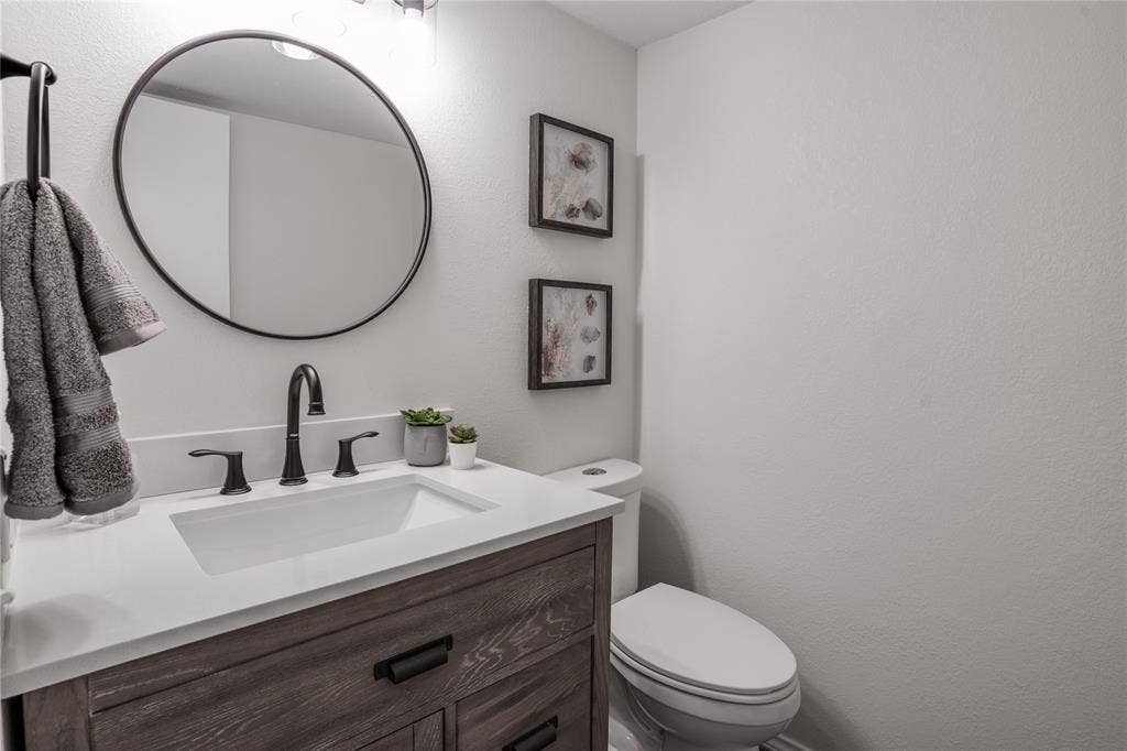 Wood-finish vanity with an integrated sink, white countertop, and matte black fixtures