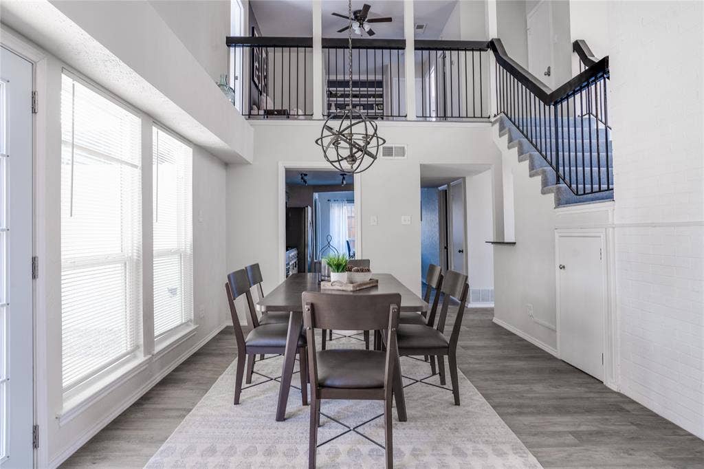 Vaulted ceiling, open concept design, wood-finish flooring, white paneled walls, and a black wrought iron staircase