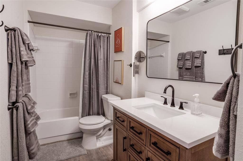 White vanity with a rectangular undermount sink, dark bronze-finish faucet, and a large framed mirror
