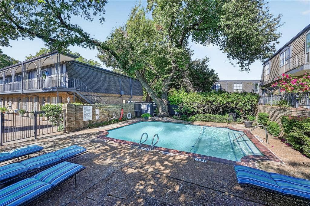 5043 Les Chateaux Drive, #214, Dallas, TX 75235 Swimming pool with brick coping, surrounded by mature trees and landscaping