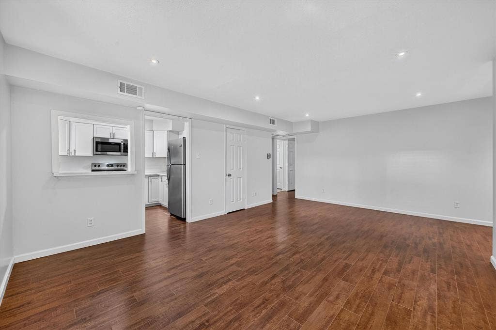 5043 Les Chateaux Drive, #214, Dallas, TX 75235 Open-concept living space featuring gleaming vinyl plank wood like finish flooring throughout, recessed ceiling lighting, and white painted interior doors