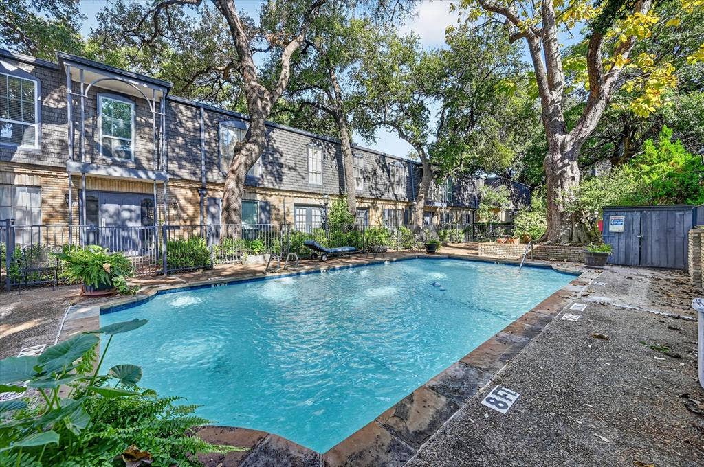 5043 Les Chateaux Drive, #214, Dallas, TX 75235 Community swimming pool with water features, surrounded by mature trees