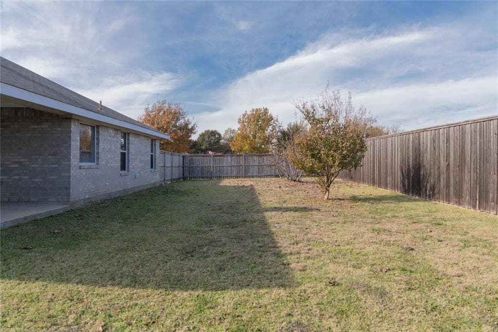 15534 Durango Drive, Frisco, TX 75035 Expansive grassy yard with a privacy fence, established trees, and a concrete patio