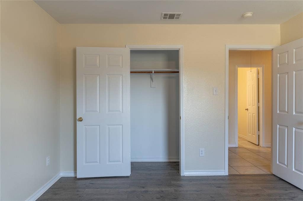 15534 Durango Drive, Frisco, TX 75035 Wood-finish flooring with light-toned walls, white panel doors, and a built-in closet with a hanging rod