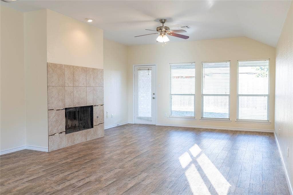 15534 Durango Drive, Frisco, TX 75035 Wood-finish flooring, tiled fireplace, ceiling fan with integrated lighting, vaulted ceiling, and multiple windows