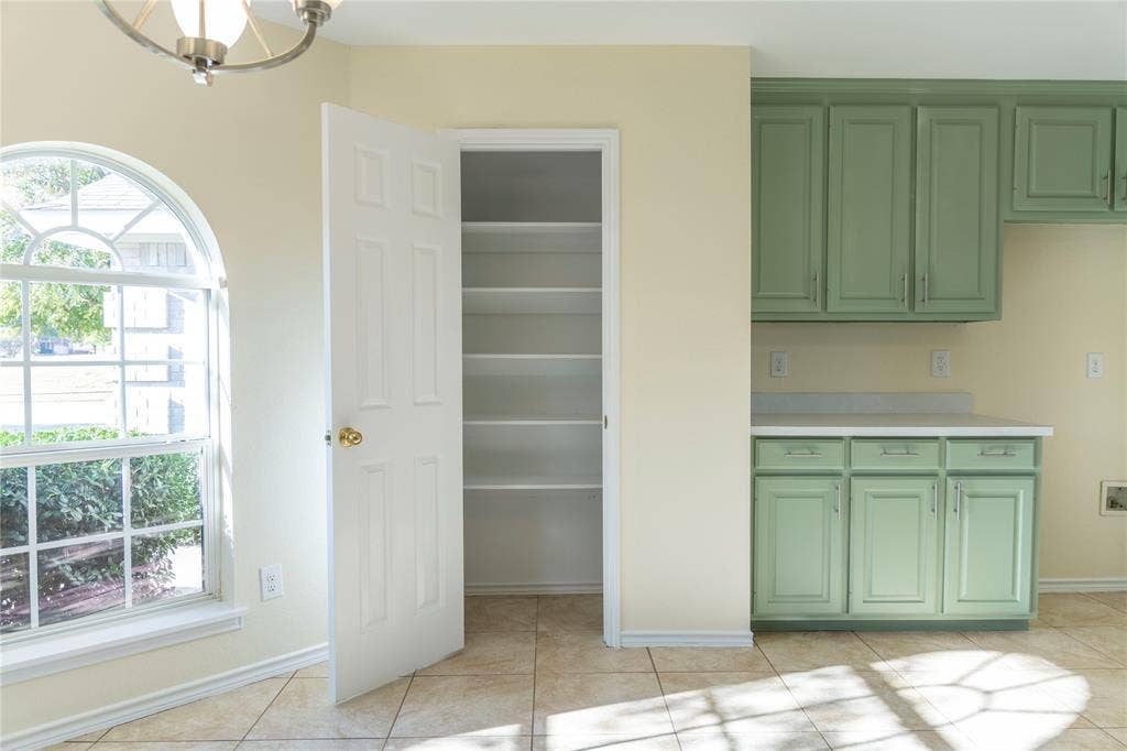 15534 Durango Drive, Frisco, TX 75035 Arched window with grilles, tile flooring, built-in shelving, paneled cabinetry, and a countertop surface
