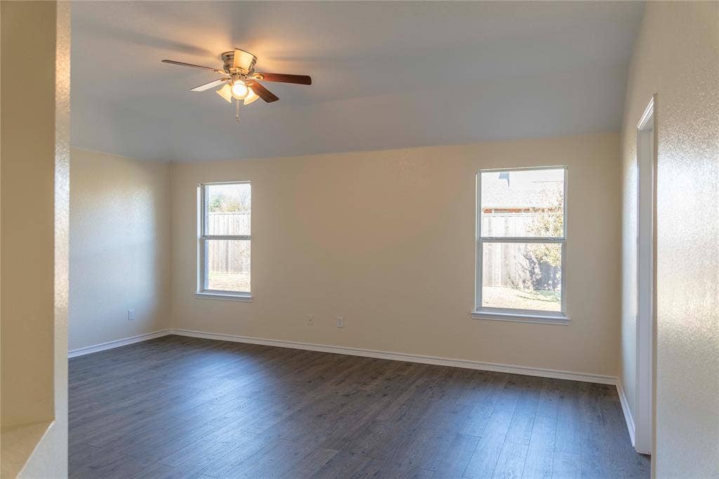 15534 Durango Drive, Frisco, TX 75035 Spacious room featuring wood-finish flooring, two large windows, a ceiling fan with integrated lighting, and neutral wall tones