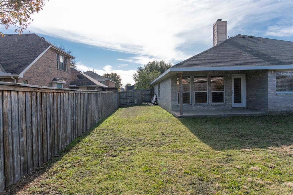 15534 Durango Drive, Frisco, TX 75035 Fenced backyard with a covered patio, brick exterior, and a shingle roof
